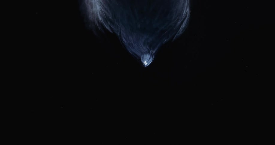 A glowing white object leaves a trail of smoke as it falls in the darkness and disintegrates