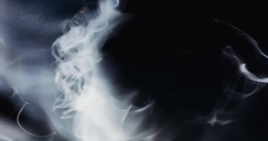 A white smokey substance with holes breaks apart and wisps moves across the darkness