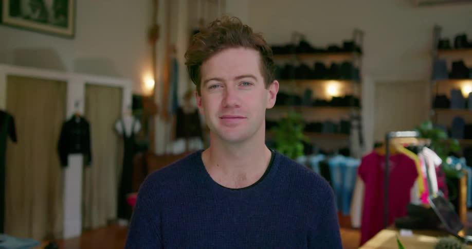 Man standing in clothing shop smiles
