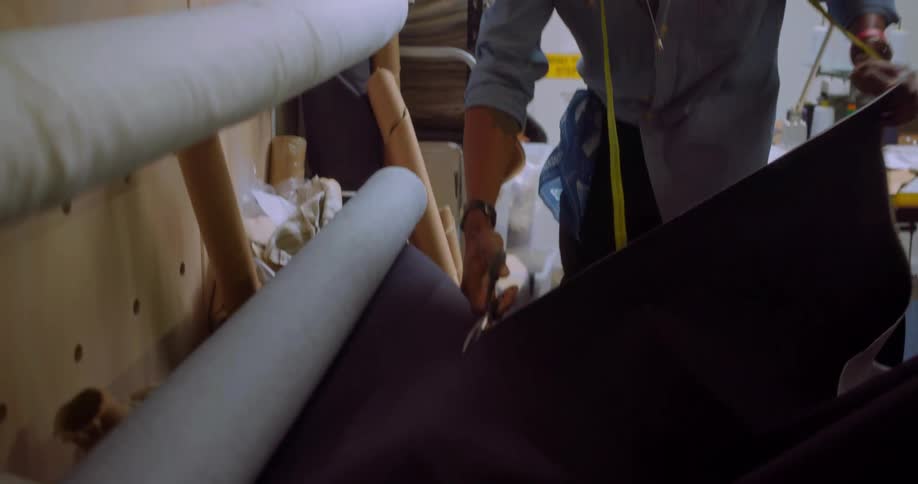 Man cuts thick black cloth with shears