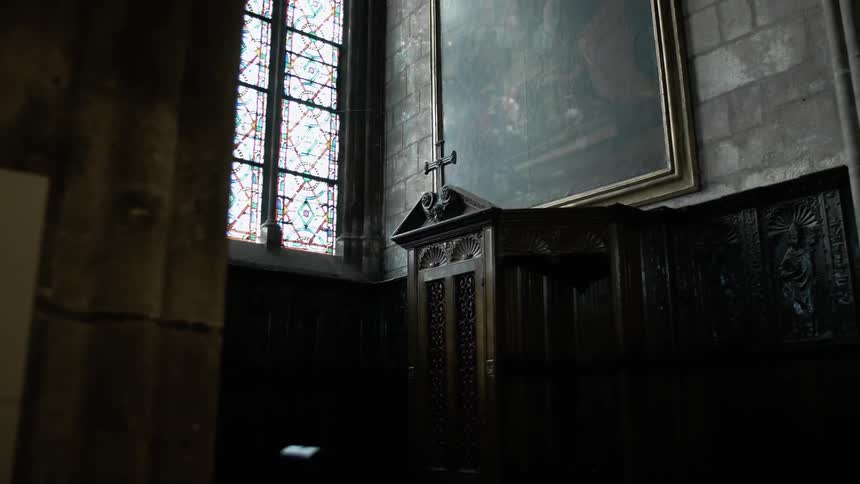 Sunlight streaming through stained-glass church windows and illuminating a tabernacle and painting