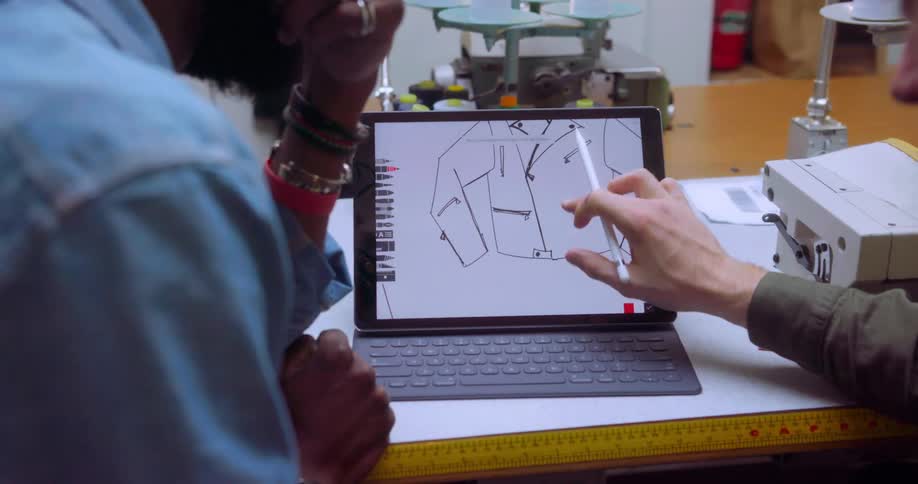 Two designers look at a jacket design on a laptop