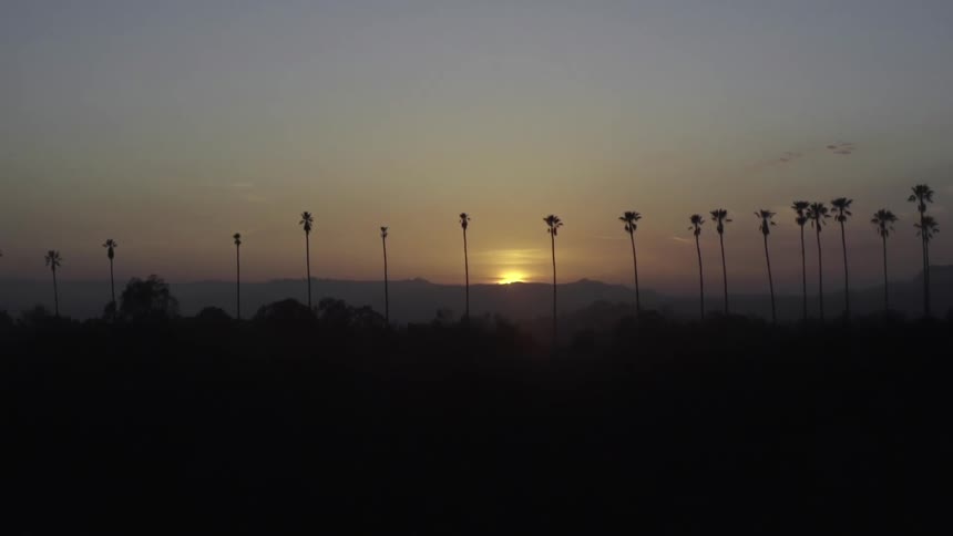 The sun is setting over the distance behind the mountains