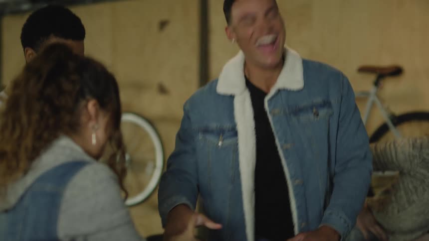 A small group of people are standing around pounding their fists on their open palms and laughing