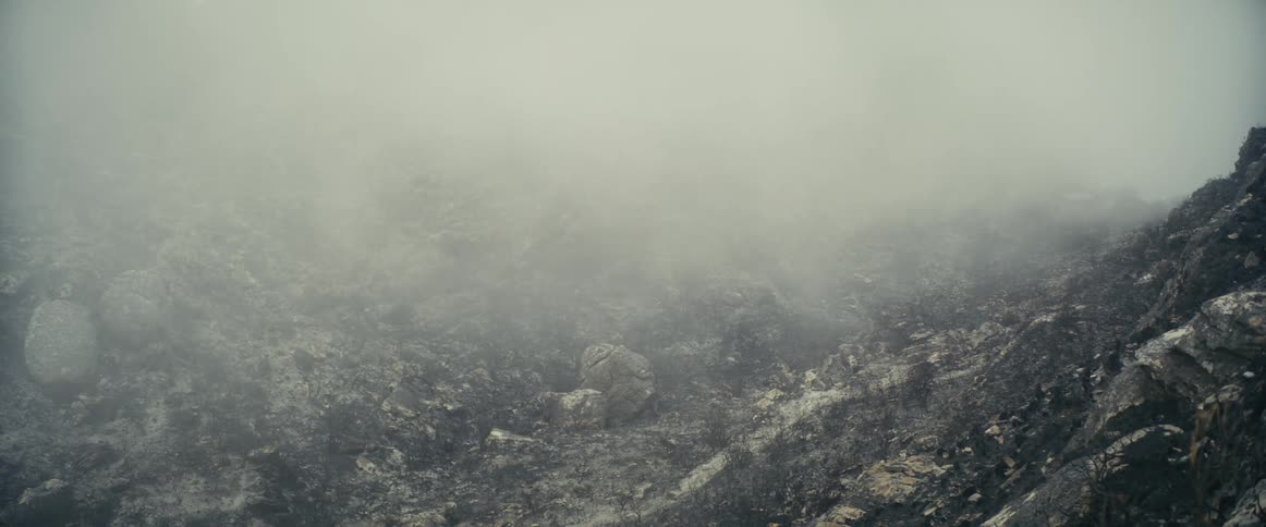 Aerial view of clouds floating over a burnt valley