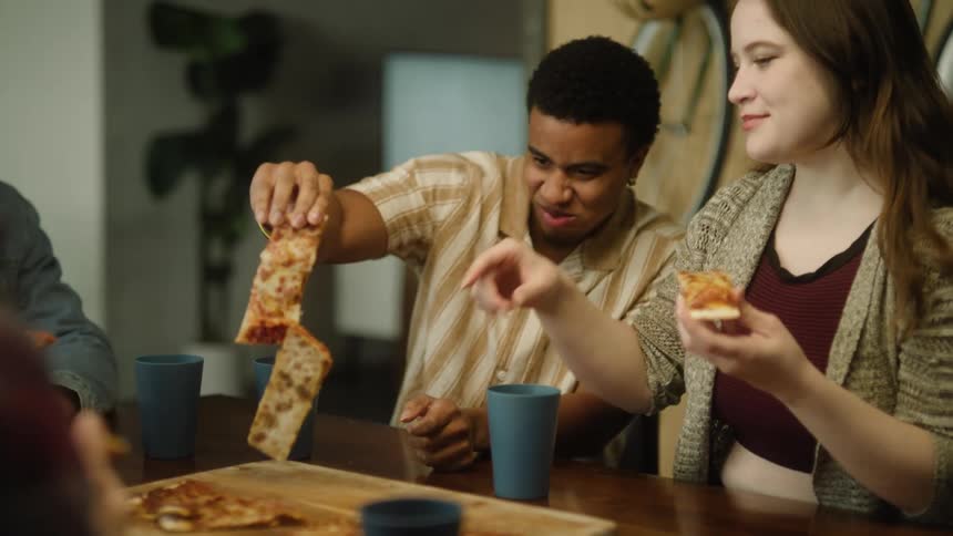 A group of friends chat while enjoying pizza together inside