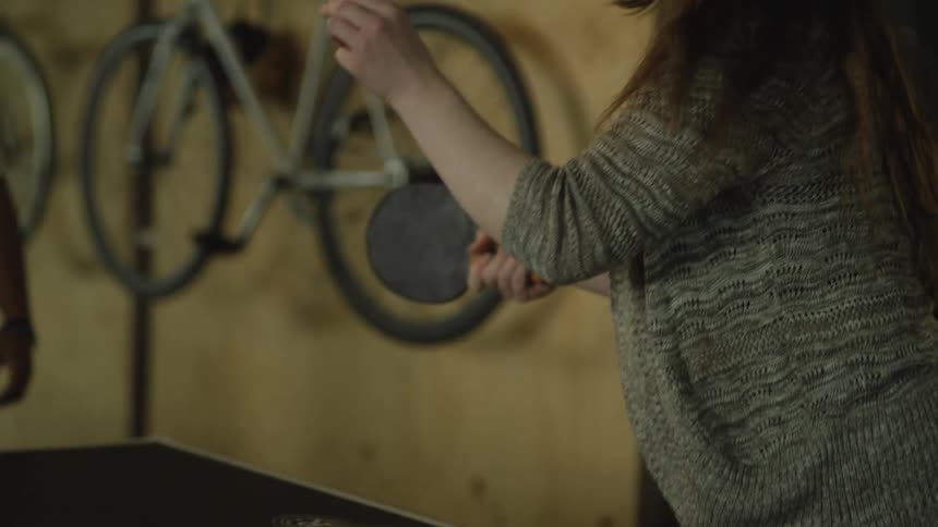 A man talks to a young woman as she plays table tennis with a smile on her face