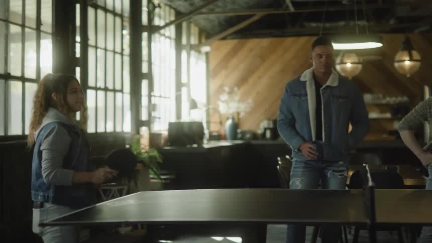 Two people are playing ping pong while their friends watch