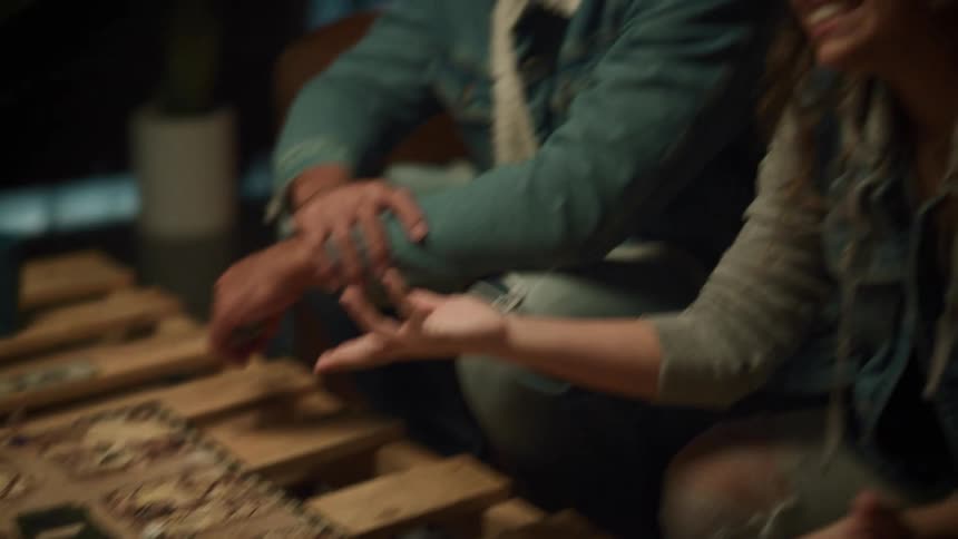 A small group of people are sitting at a table playing a board game