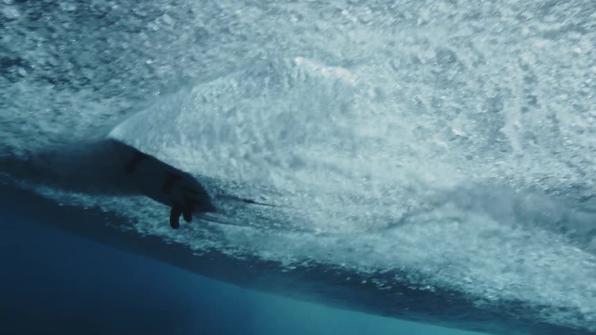 Surfer uses surfboard for surfing on water
