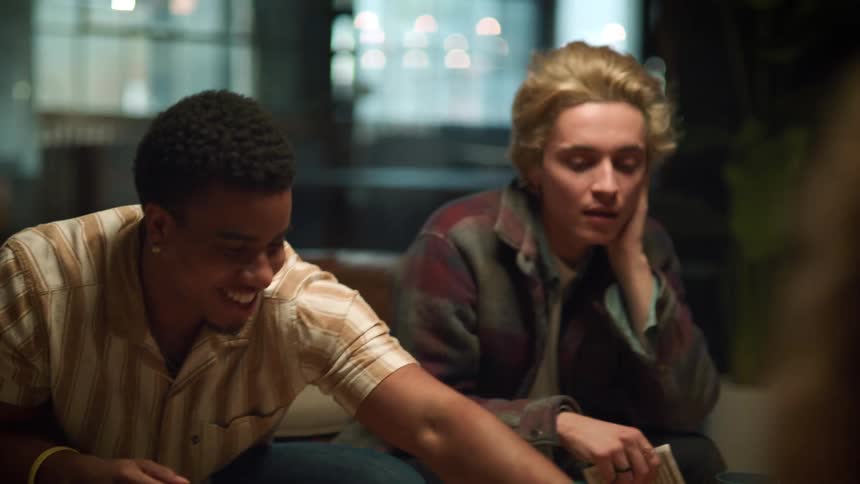 A teenage boy rolls a dice as he plays a game with his friends
