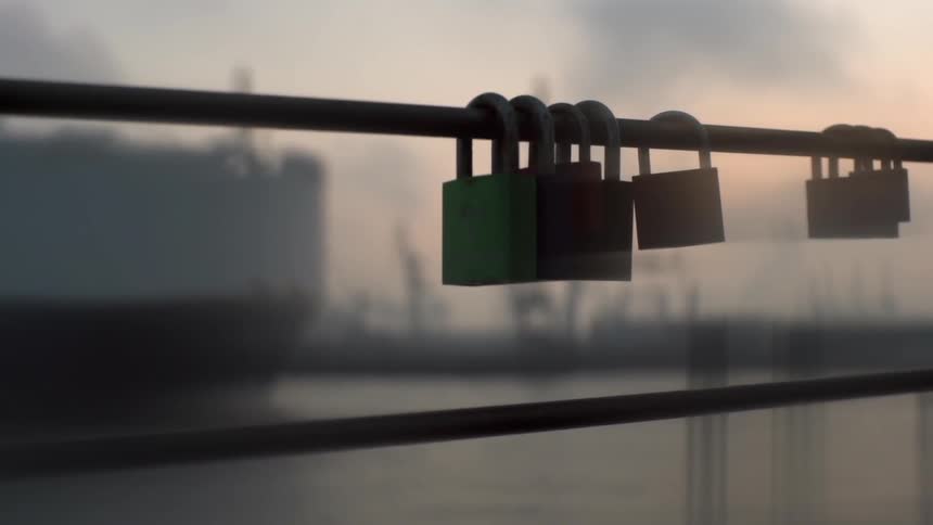 Locks are attached to this railing with a ship in the water
