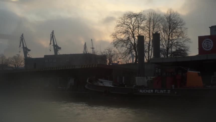 A boat docked along an urban waterfront under dark clouds
