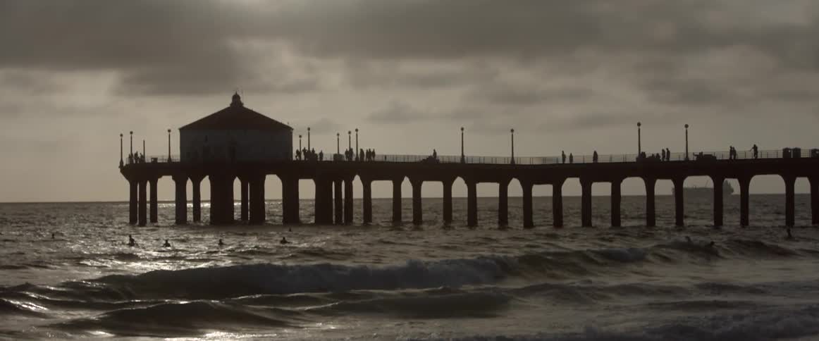 Waves roll onto a beach near a pier