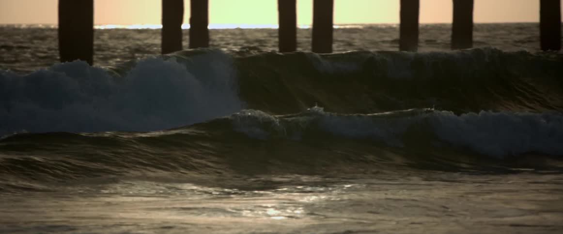 Waves form and crash near a pier