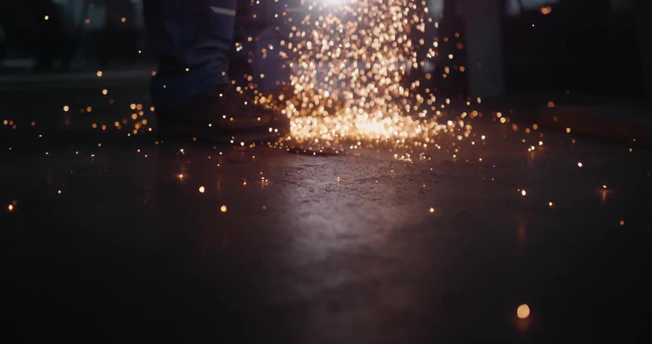 Welding spark embers hit the floor around the welders booted feet