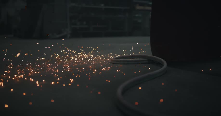 Bright glowing sparks are falling on the floor of a workshop