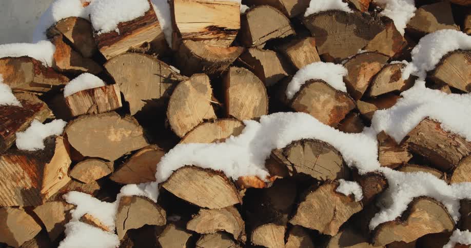 Chopped up lumber stacked in a pile with snow on it