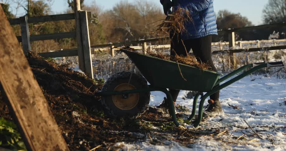 A woman cleans up a pile of dirt and weeds on her farm