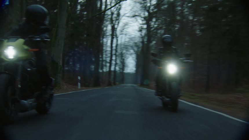 One person is riding a motorcycle as it goes on it pans to another person on their left riding next to them