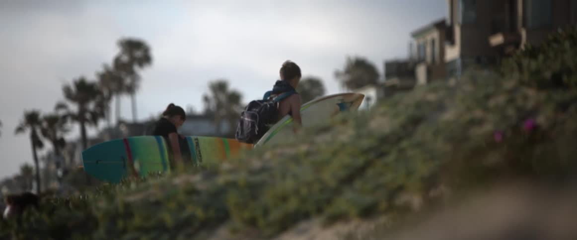 Surfers carry their surfboards on the beach