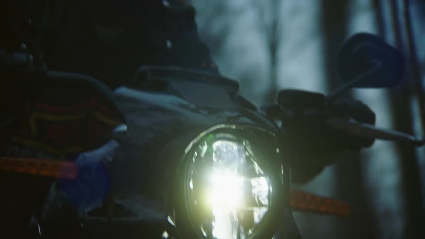 A person drives a motorcycle at night