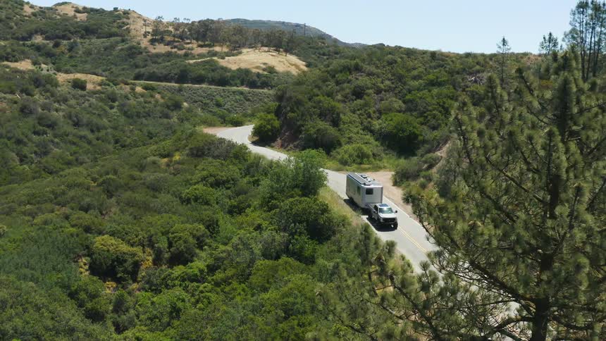 A truck with a trailer attached traveling down the road