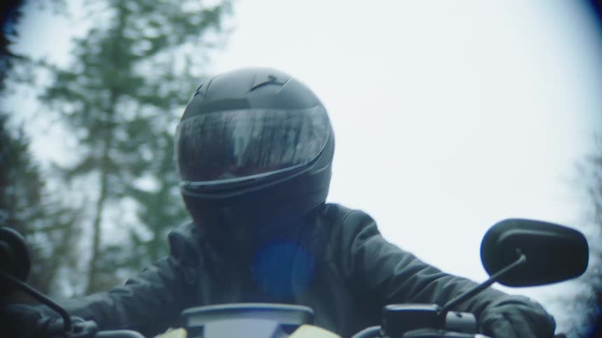 A woman is riding a yellow motorcycle on the road