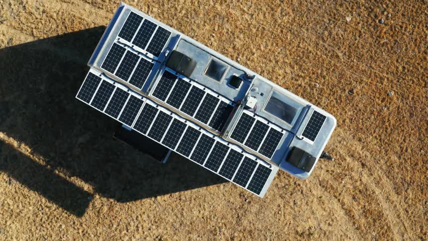 A structure with grids on the roof sitting on a dirt area