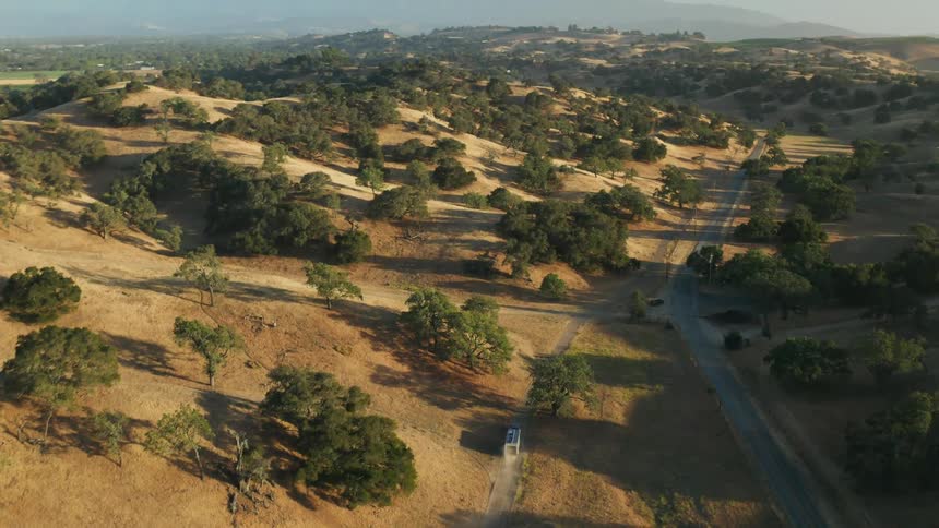 A truck pulls a mobile home on a road through hills and mountains with many trees