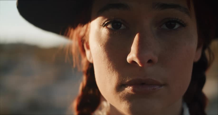 Close up of the face of a woman wearing a hat outdoors looking at the camera