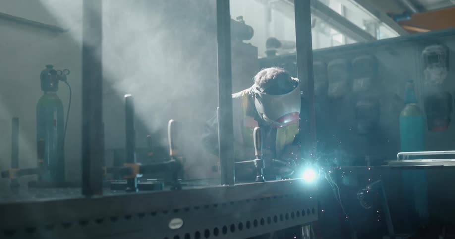 A welder using a torch in a workshop causing sparks and embers to fly