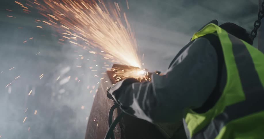 Sparks fly as a worker files a piece of metal using a torch in the warehouse