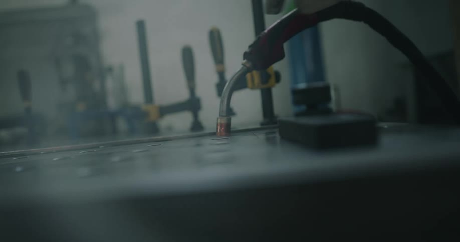 Person wearing protective gear sets hose nozzle into workbench hole