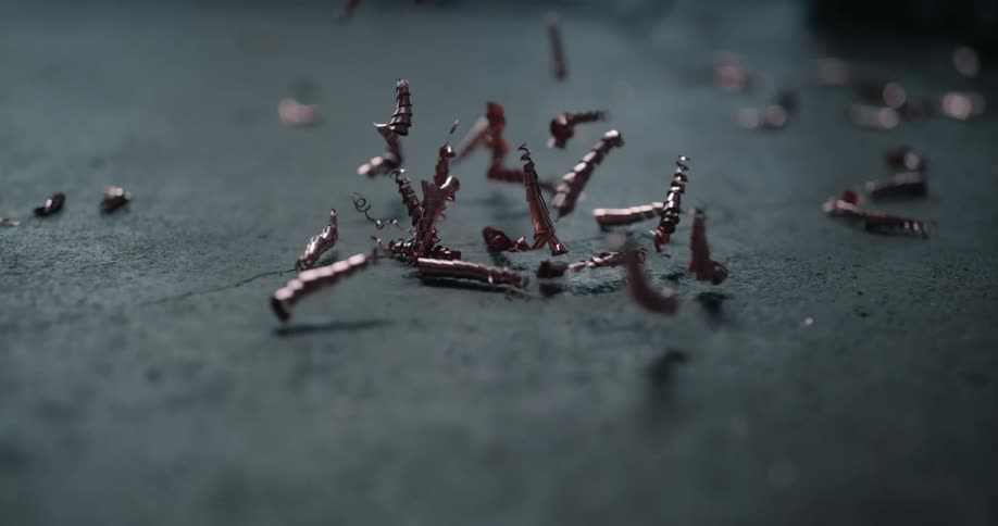 Metal shavings are falling and bouncing when they hit the floor