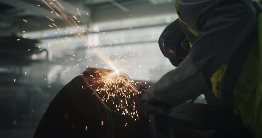 Sparks fly as a worker cuts a piece of metal using a torch in the warehouse