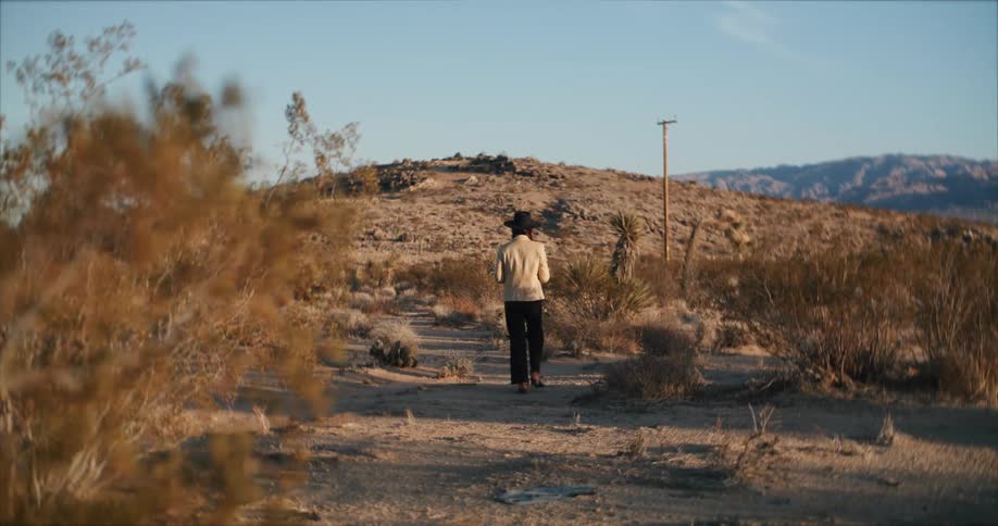A woman walks towards a hill in the countryside