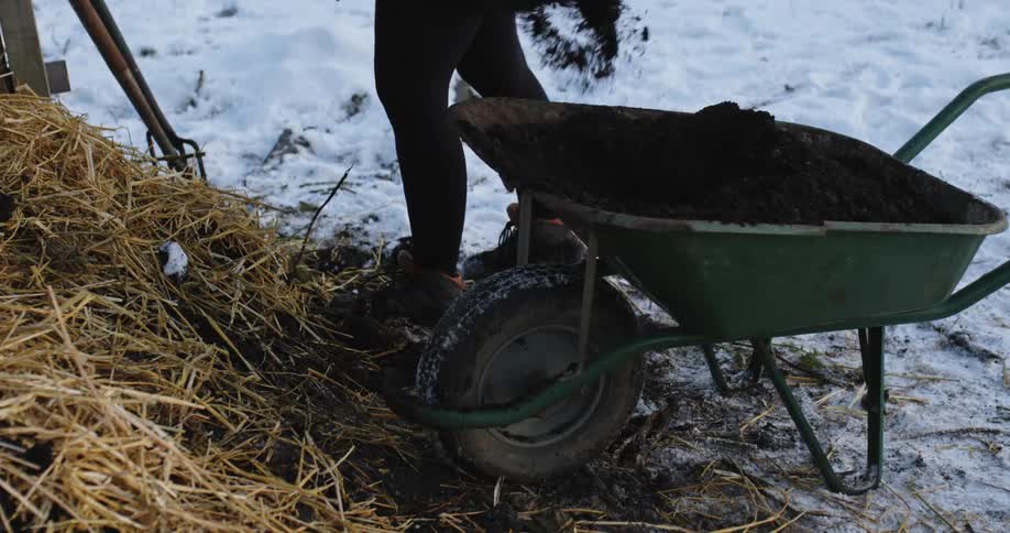 A person shovels out dirt on to straw