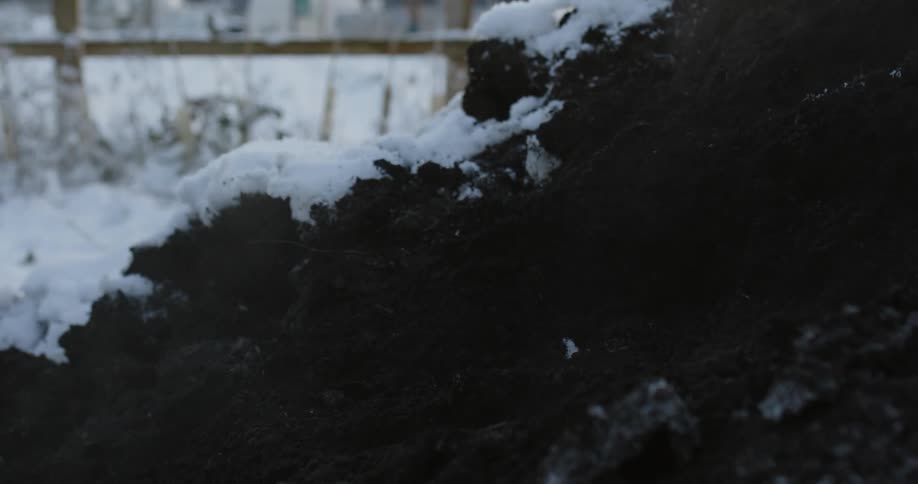 A person shoveling snow covered dirt