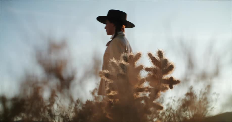 Woman walks across behind a cactus