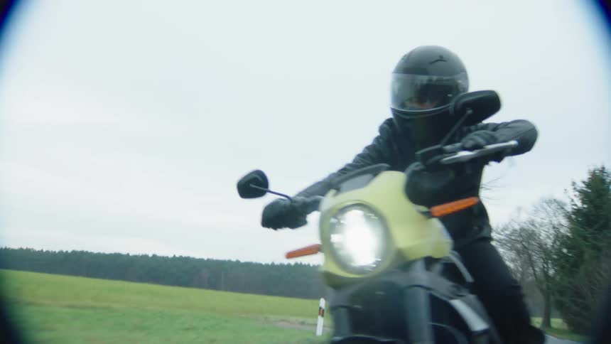 A motorcyclist in a helmet speeding down a rural road