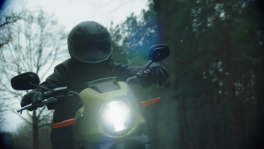 Motorcyclist drives quickly along highway through woods