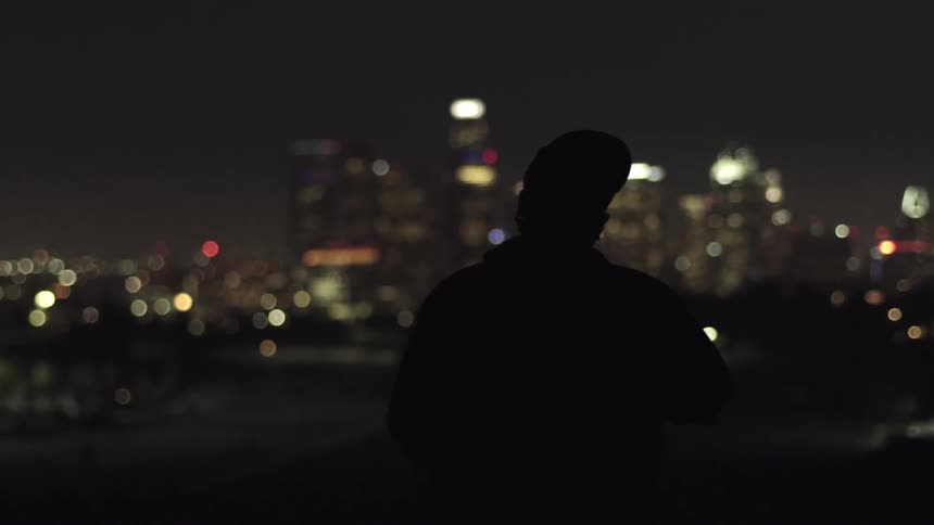 A man adjusts his hat outside at night
