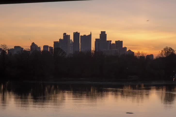 The sun rises behind a city