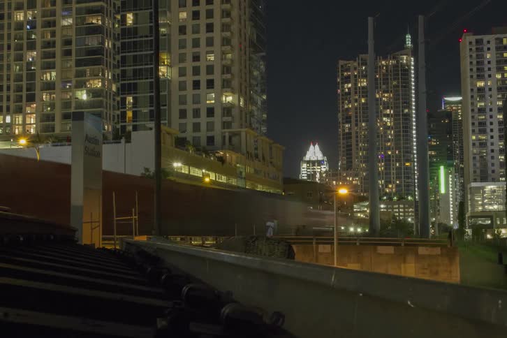 Traffic and a train passing through a well-lit city at night