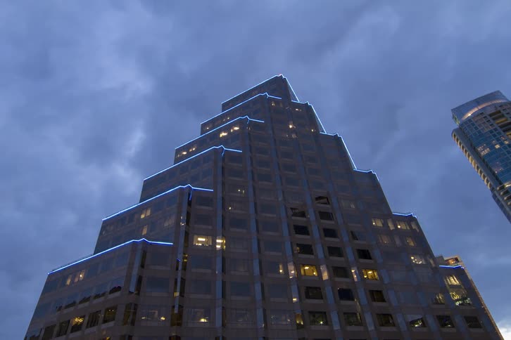 Clouds roll over a high-rise as lights come on inside and outside the building