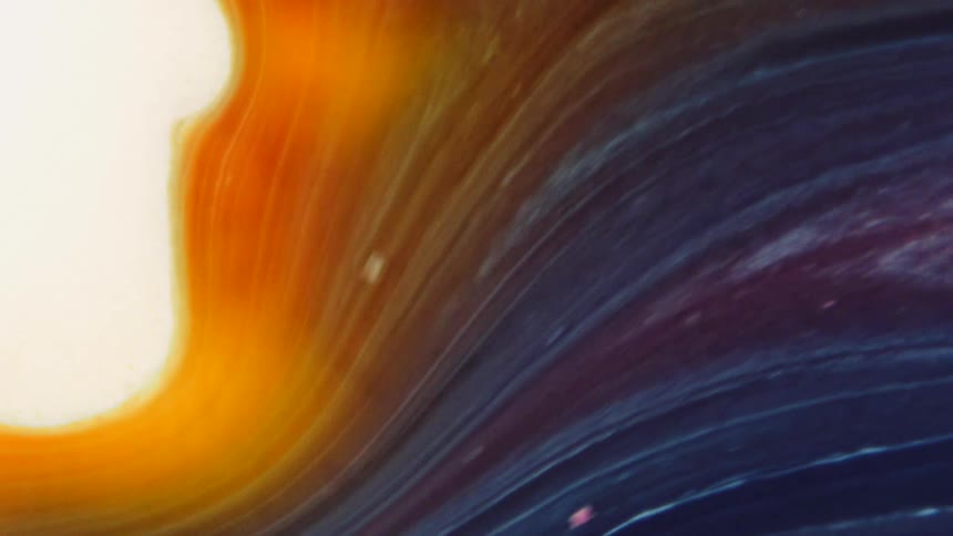 Orange and blue striped liquid flows near a bright glowing substance