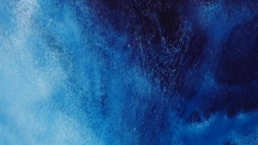 A viscous blue liquid grows darker as it spills down