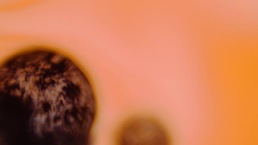 A gray textured orb is breathing as it sits on an orange surface