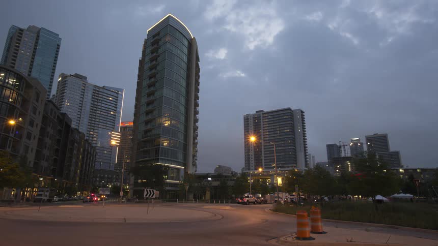 Vehicles and clouds moving in a city night changes to day